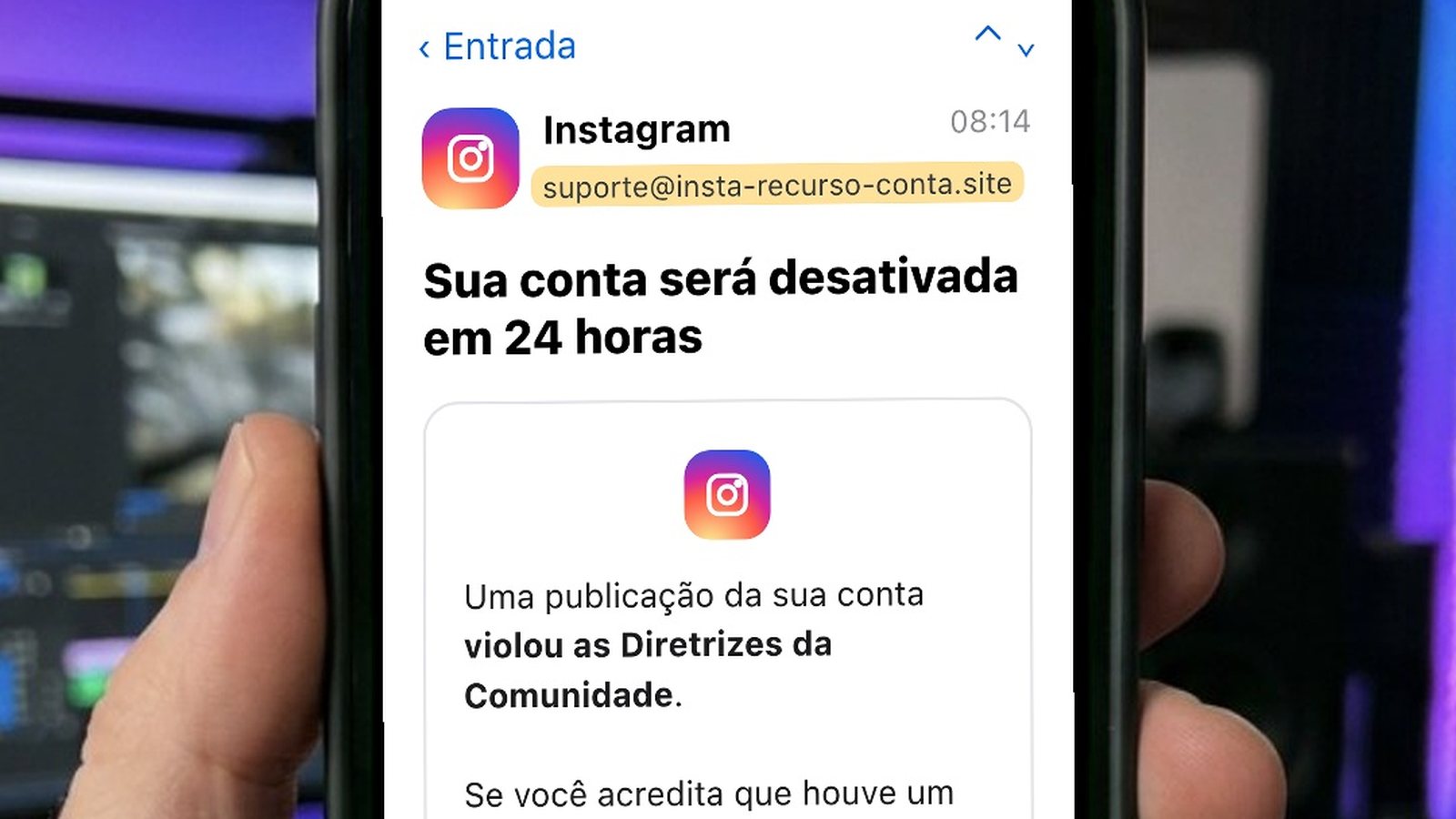 Mão segurando um celular com um e-mail falso em nome do Instagram, enviado de um endereço estranho, avisando que a conta será desativada em 24 horas e com um botão azul de enviar recurso